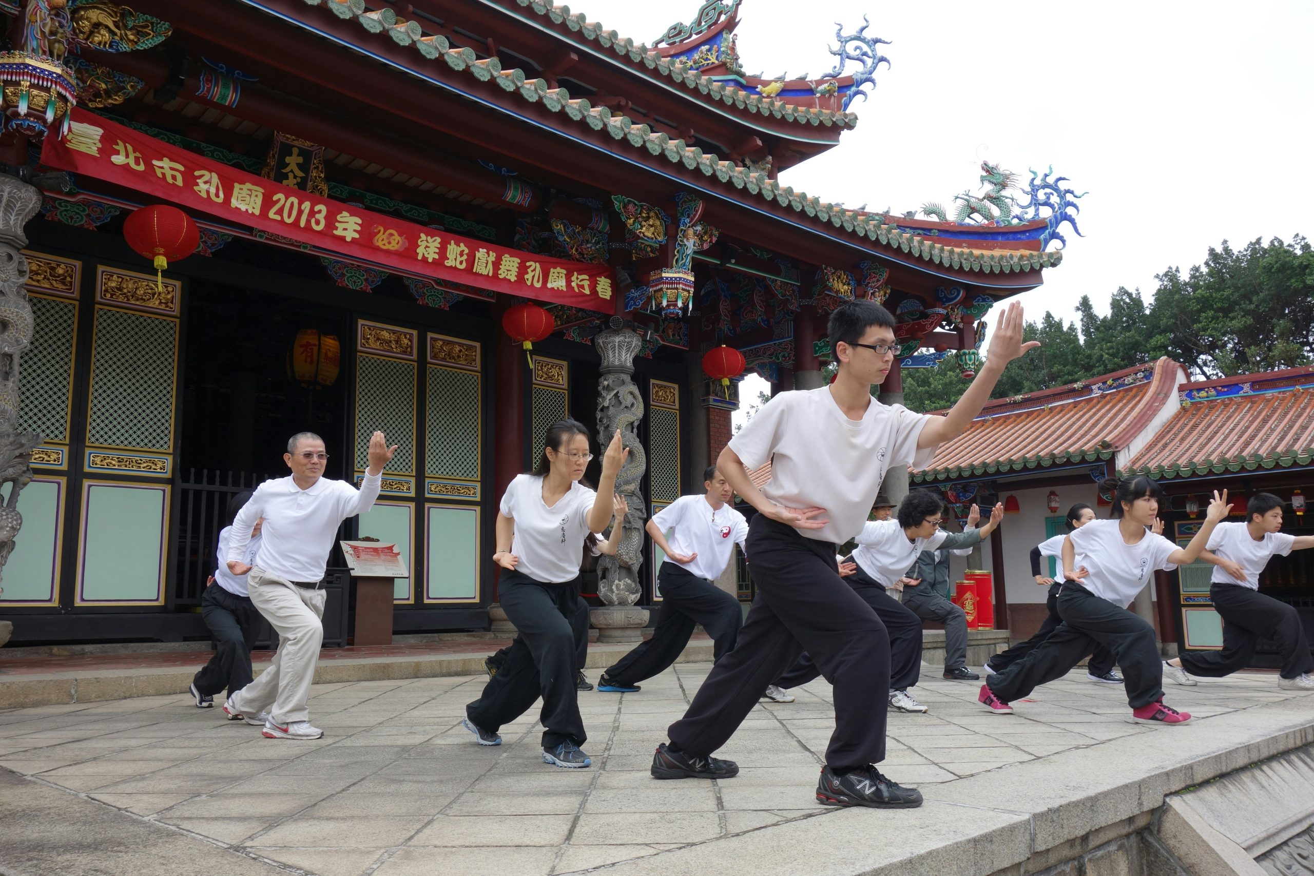 A welcoming, multi-generational group of adults practicing traditional Kung Fu together