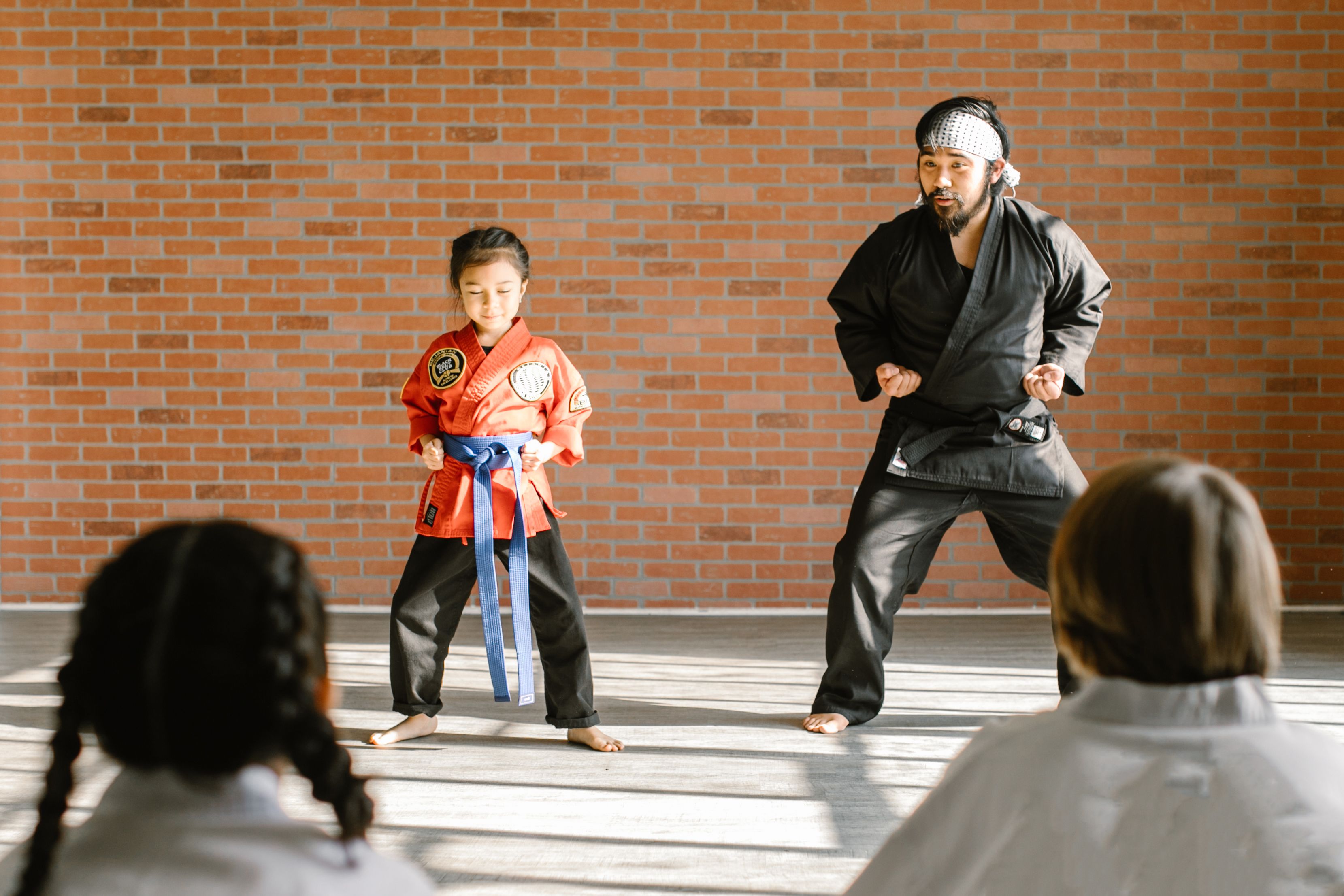 A Kung Fu instructor supporting a child student through a training stance